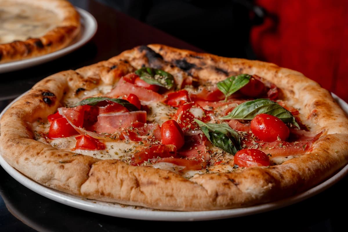 The pizza with prosciutto, tomatoes, basil and cheese.